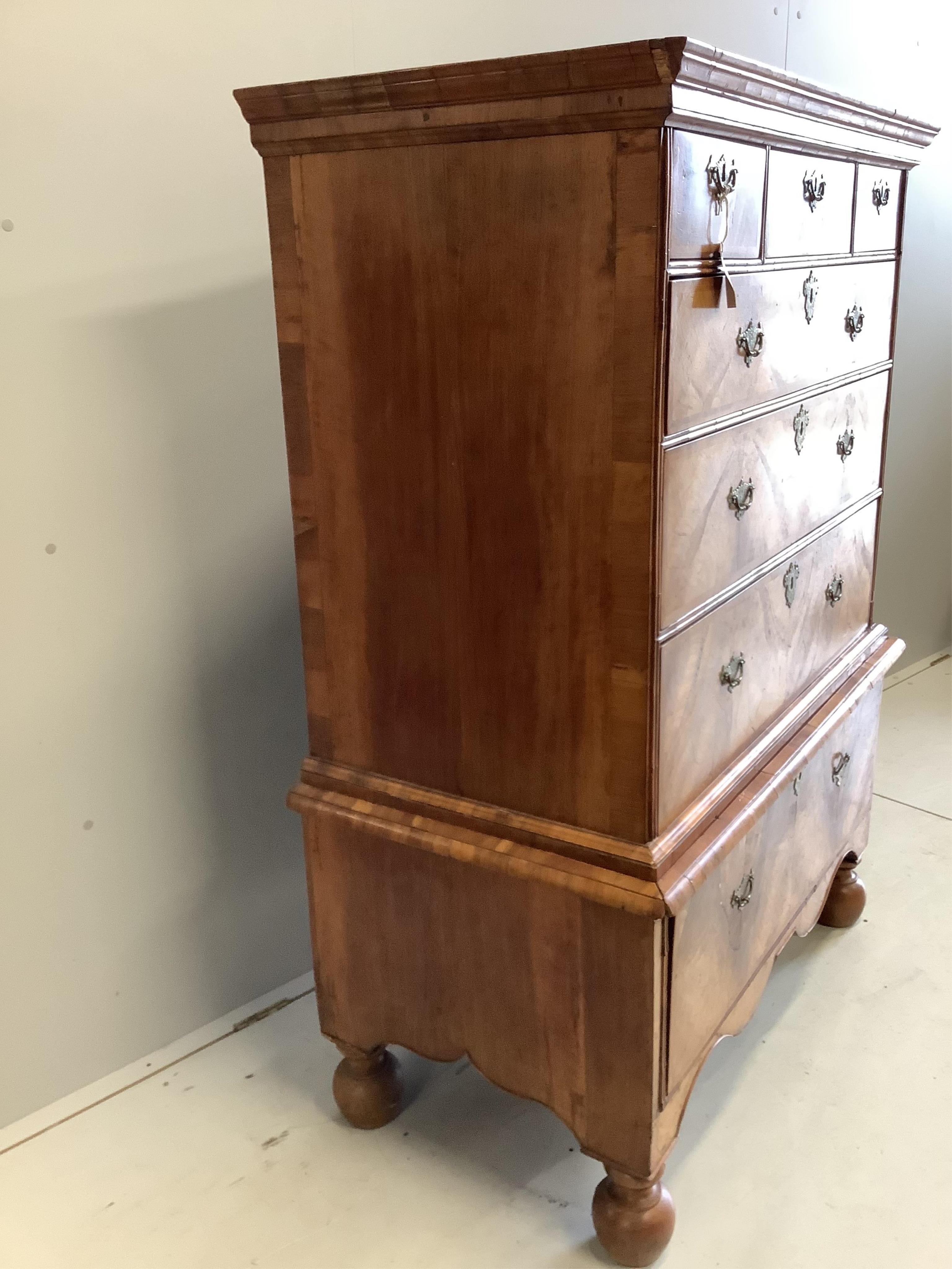 An early 18th century walnut chest on stand with later bun feet, width 106cm, height 147cm. Condition - fair